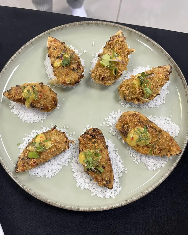 Ostras empanadas gratinadas servidas sobre sal grosso, preparado pela Chef Angie
